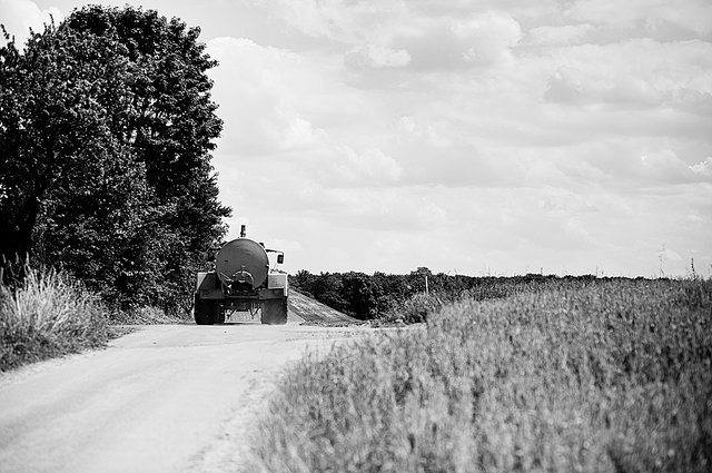 Ein Traktor mit einem Spritzmittelanhänger fährt über einen Feldweg